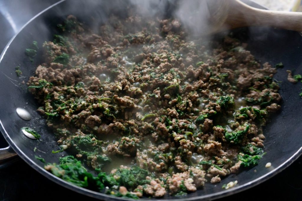 ground beef and spinach browned in a pan 