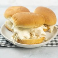 Instant Pot Alabama White Sauce Sliders on a white plate with gray plaid napkin and concrete back drop