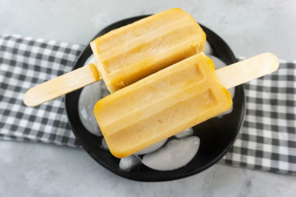 Pumpkin Latte Popsicles on a black plate with gray plaid napkin on a concrete backdrop