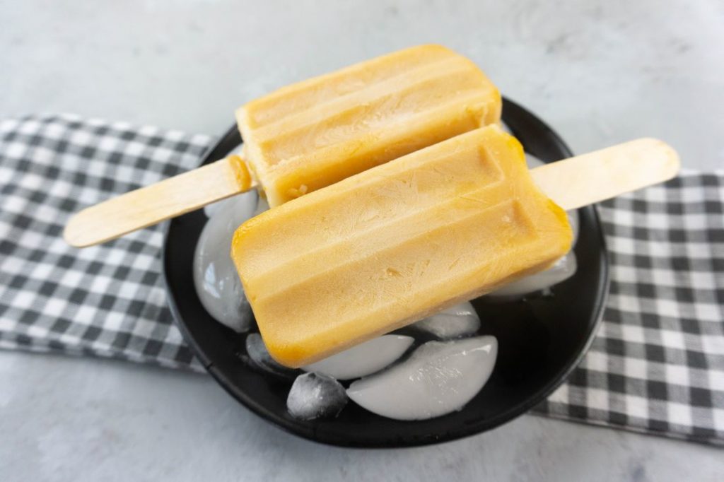 Pumpkin Latte Popsicles on a black plate with gray plaid napkin on a concrete backdrop