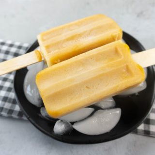 Pumpkin Latte Popsicles on a black plate with gray plaid napkin on a concrete backdrop