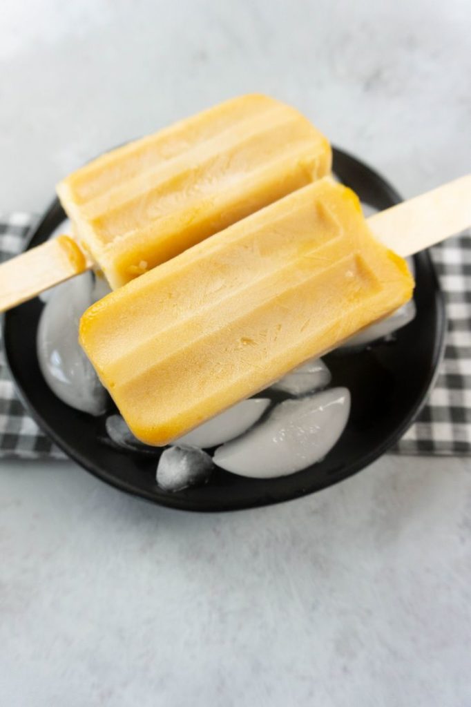 Pumpkin Latte Popsicles on a black plate with gray plaid napkin on a concrete backdrop