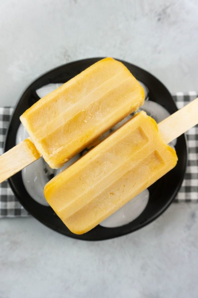 Pumpkin Latte Popsicles on a black plate with gray plaid napkin on a concrete backdrop