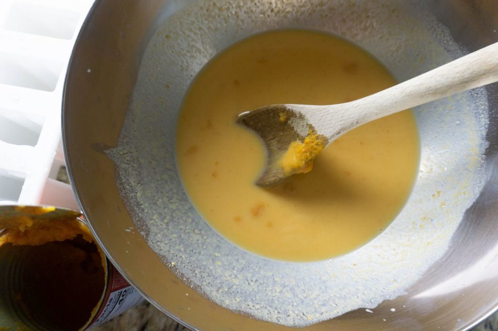 Pumpkin latte mixture in a silver bowl with a wood spoon