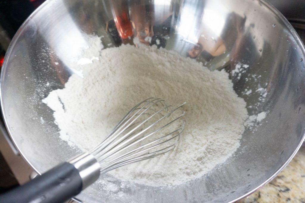 flour in a silver metal bowl with whisk