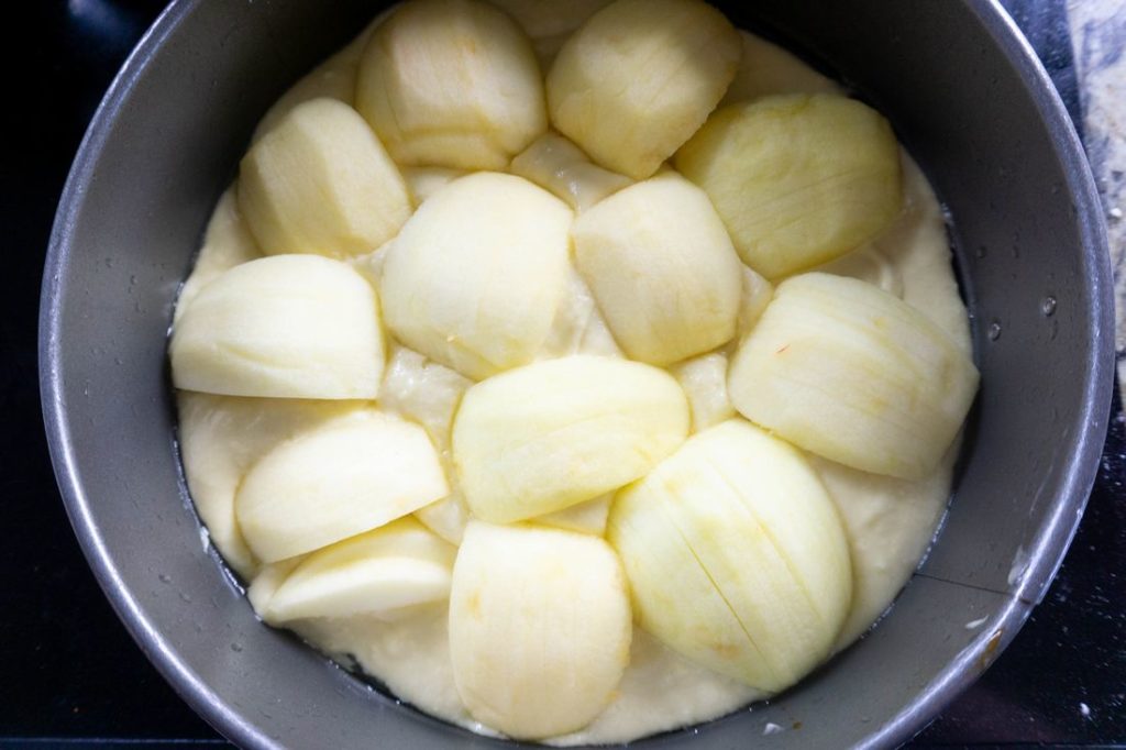 german apple cake batter in the springform pan with sliced apples