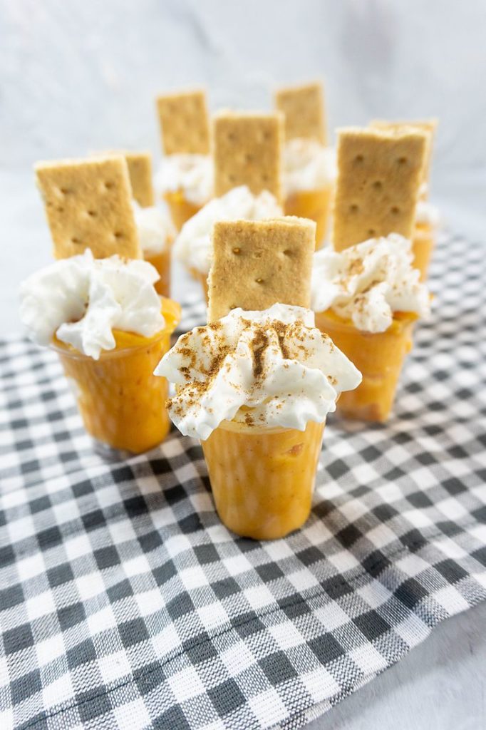 Pumpkin Pie Pudding Shots on a plaid napkin and concrete back drop