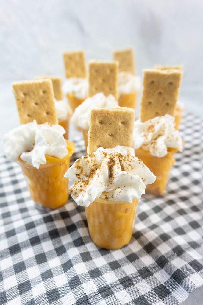 Pumpkin Pie Pudding Shots on a plaid napkin and concrete back drop