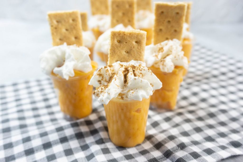 Pumpkin Pie Pudding Shots on a plaid napkin and concrete back drop