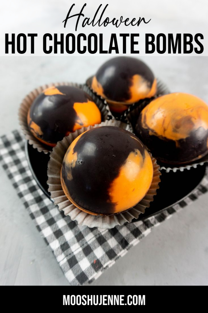 Halloween Hot Chocolate Bombs in orange and black marbled spheres on a black plate and grey plaid napkin