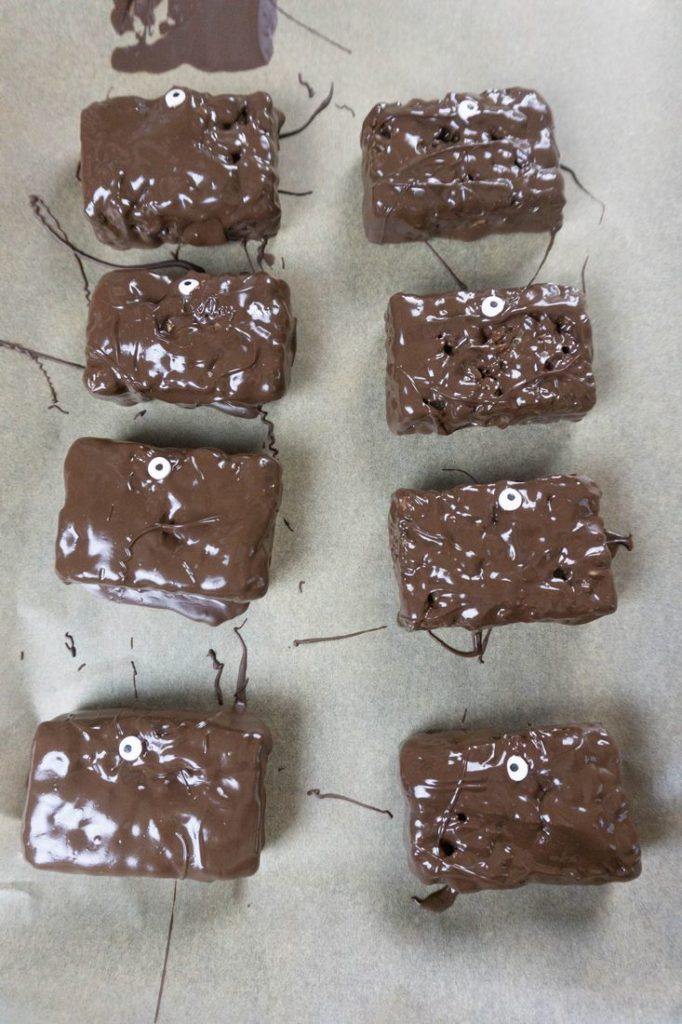 Rice krispies treats dipped in chocolate with candy eyes