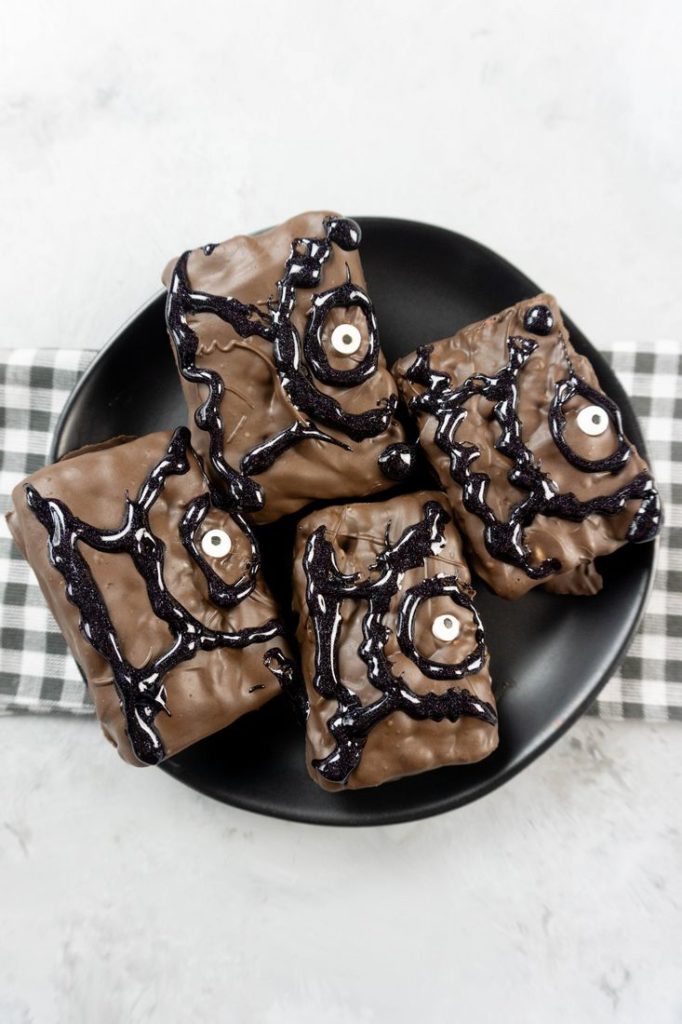Hocus Pocus Spell Book Krispies on a black plate with grey plaid napkin on a concrete backdrop