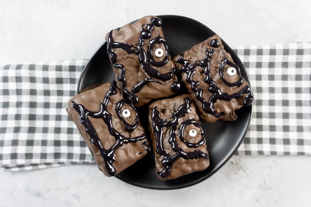 Hocus Pocus Spell Book Krispies on a black plate with grey plaid napkin on a concrete backdrop