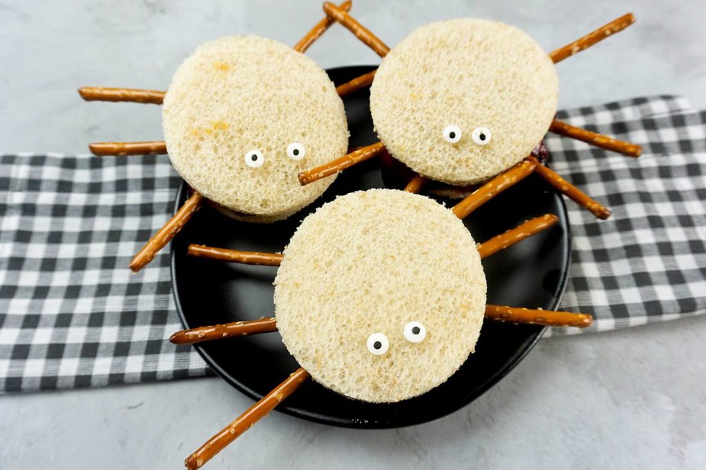 Spooky Spider Sandwiches on a black plate with a gray plaid napkin