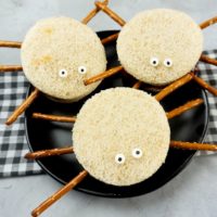 Spooky Spider Sandwiches on a black plate with a gray plaid napkin