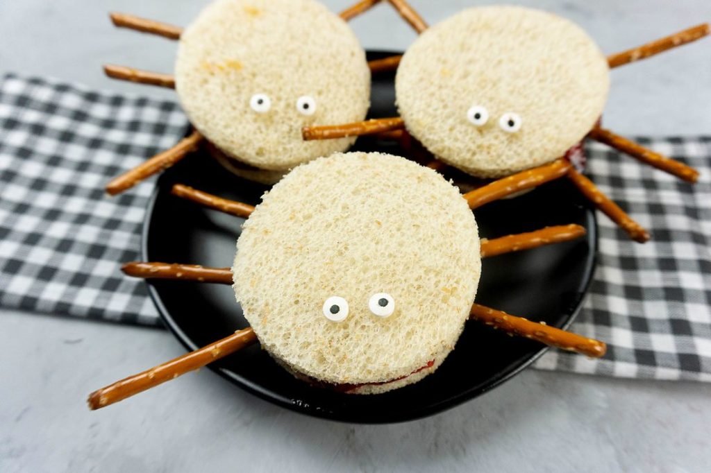 Spooky Spider Sandwiches on a black plate with a gray plaid napkin