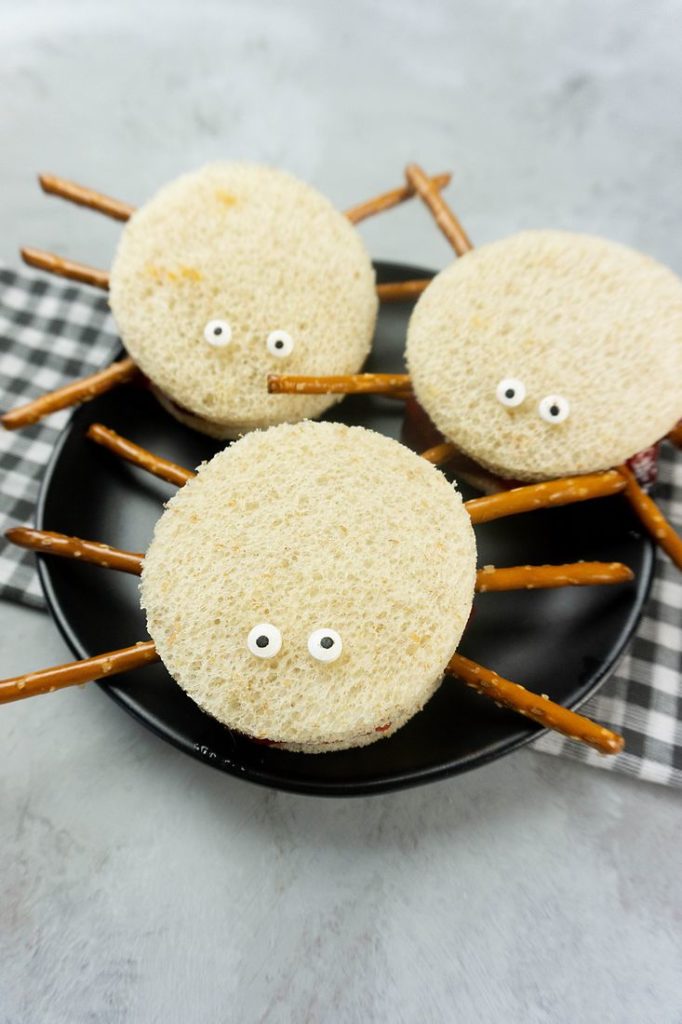 Spooky Spider Sandwiches on a black plate with a gray plaid napkin