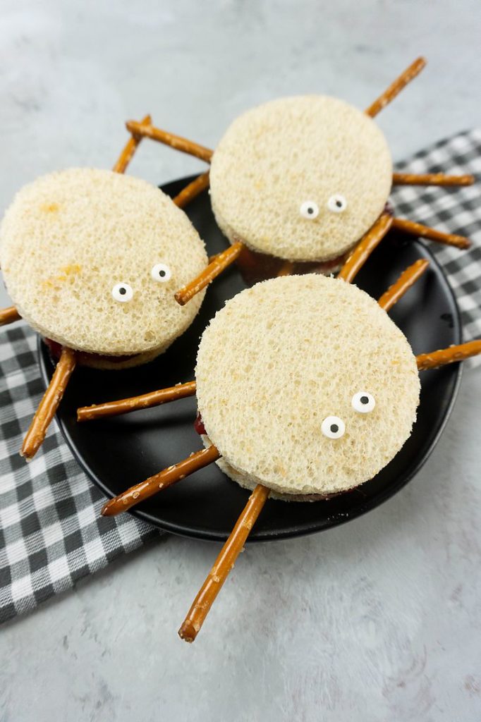 Spooky Spider Sandwiches on a black plate with a gray plaid napkin
