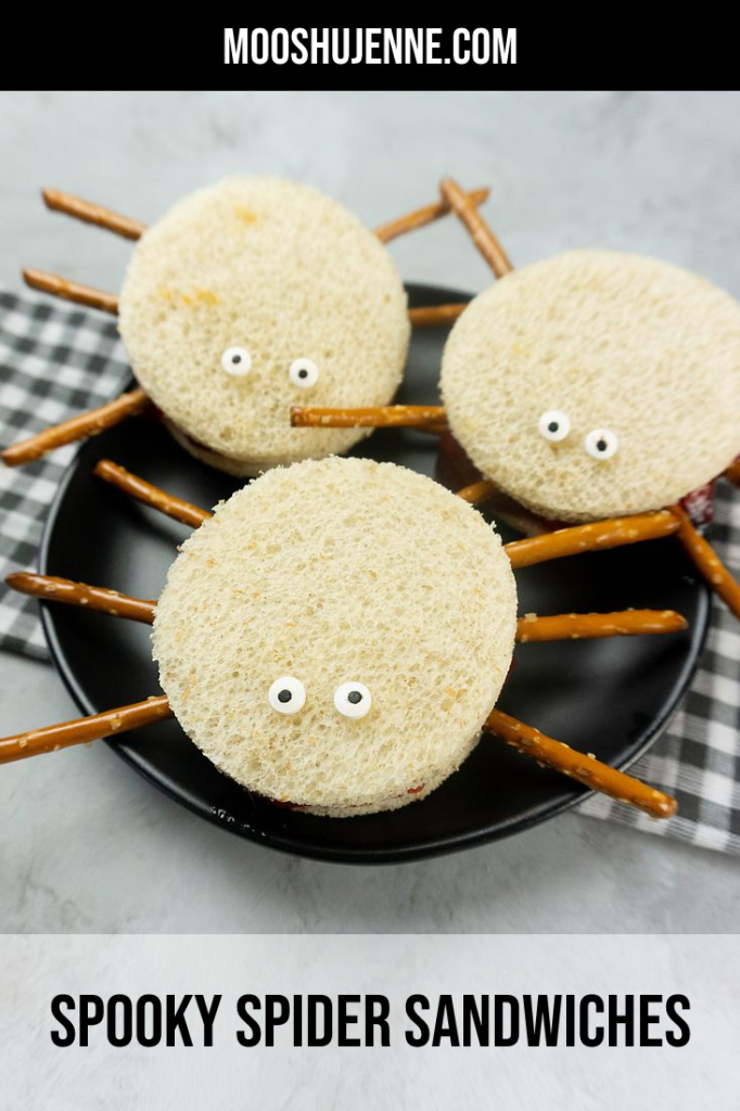 Spooky Spider Sandwiches on a black plate with a gray plaid napkin