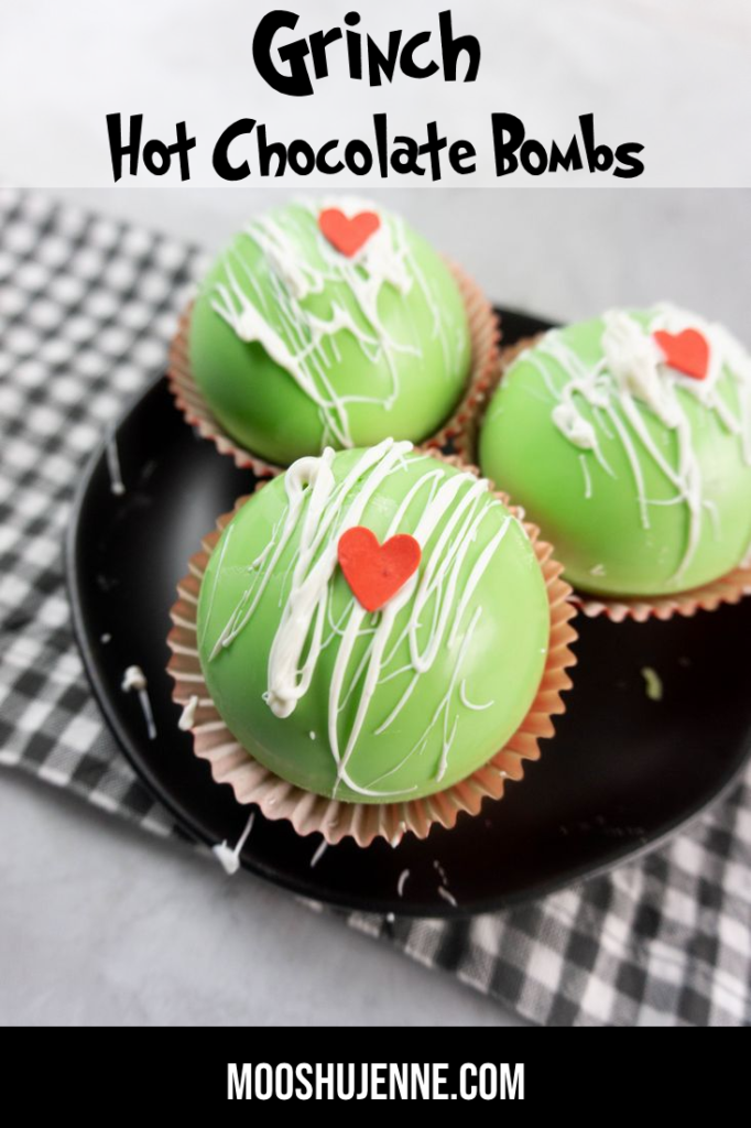 Grinch Hot Chocolate Bombs on a black plate on a grey plaid napkin with a concrete backdrop