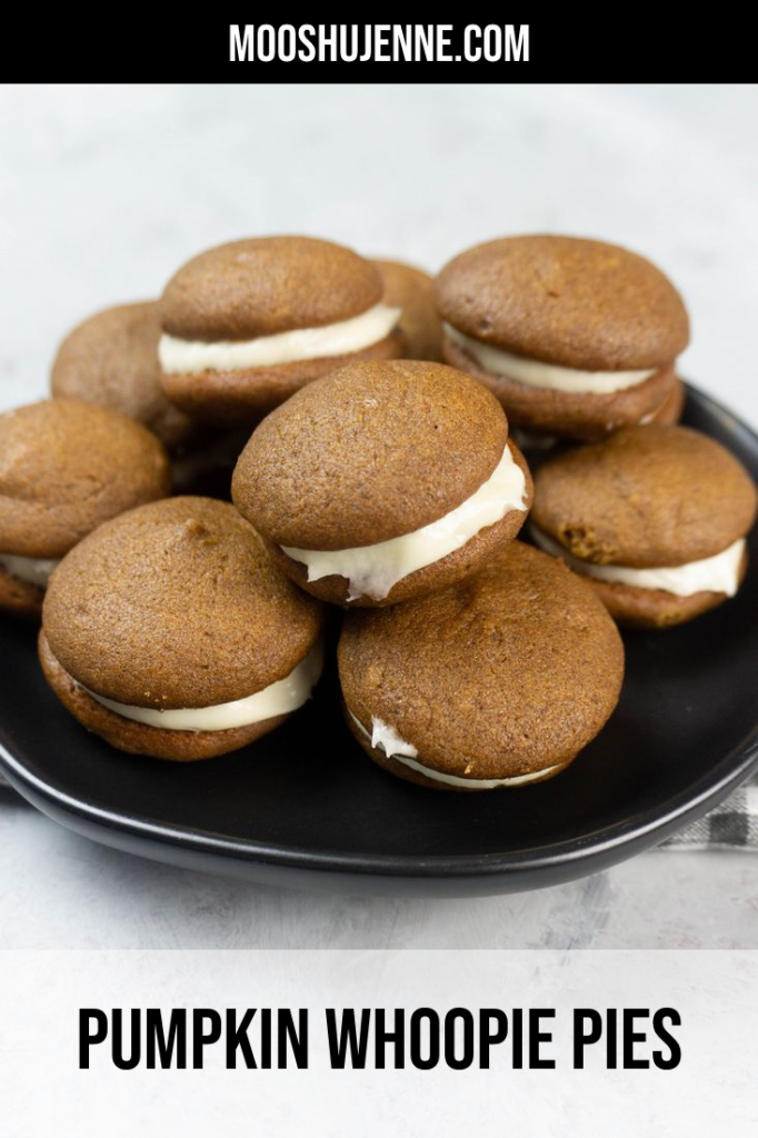 Pumpkin Whoopie Pies on a black plate with gray and white plaid napkin on a concrete backdrop