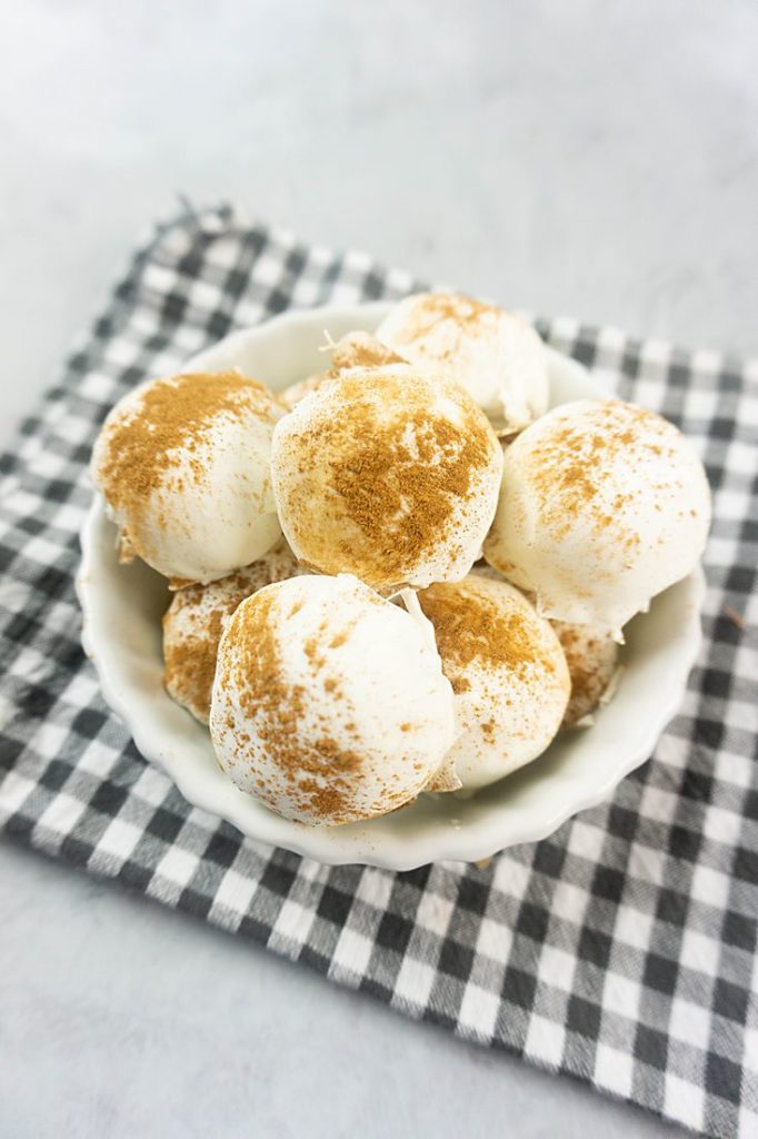 Cinnamon Golden Oreo Truffles in a white bowl with gray plaid napkin on concrete backdrop