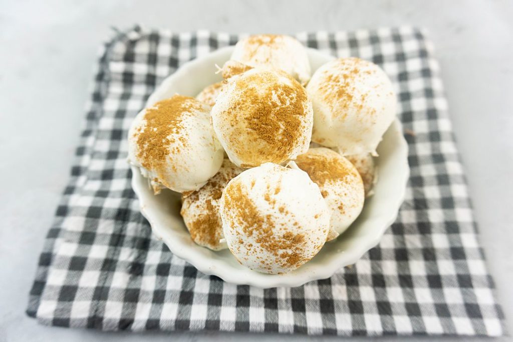 Cinnamon Golden Oreo Truffles in a white bowl with gray plaid napkin on concrete backdrop