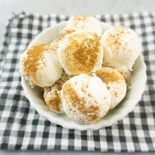 Cinnamon Golden Oreo Truffles in a white bowl with gray plaid napkin on concrete backdrop