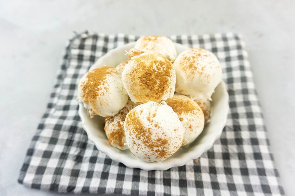 Cinnamon Golden Oreo Truffles in a white bowl with gray plaid napkin on concrete backdrop