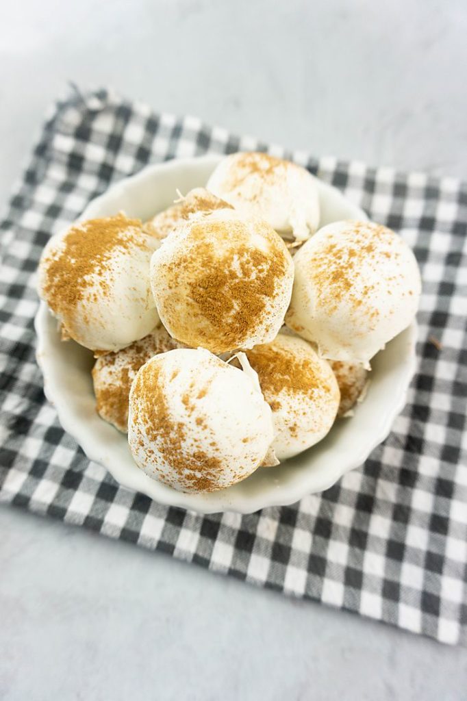 Cinnamon Golden Oreo Truffles in a white bowl with gray plaid napkin on concrete backdrop