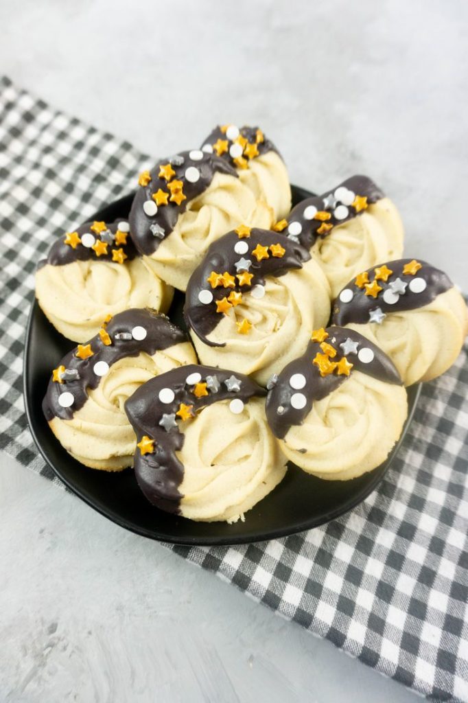 New Year's Eve Dipped Butter Cookies on a black plate with gray plaid napkin and concrete backdrop