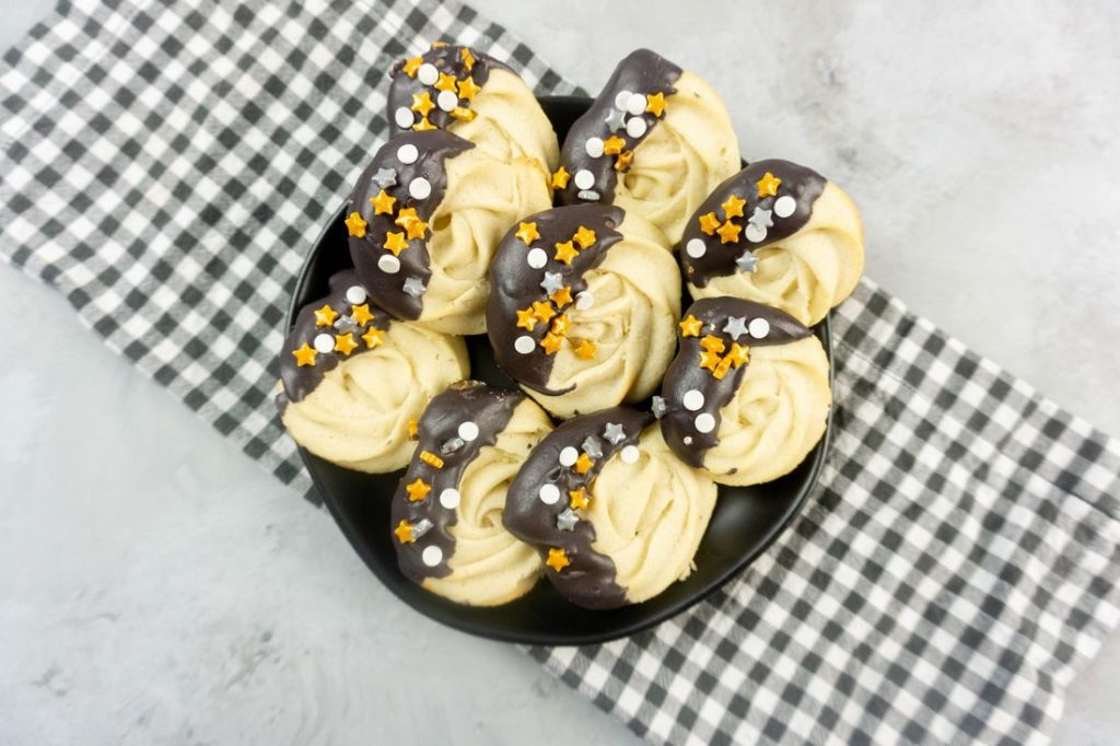 New Year's Eve Dipped Butter Cookies on a black plate with gray plaid napkin and concrete backdrop