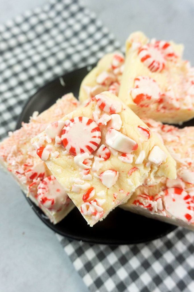 Peppermint Candy Fudge on a black plate with gray plaid napkin on a concrete backdrop