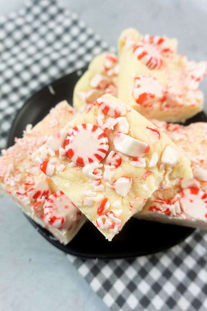 Peppermint Candy Fudge on a black plate with gray plaid napkin on a concrete backdrop