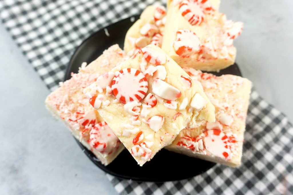 Peppermint Candy Fudge on a black plate with gray plaid napkin on a concrete backdrop