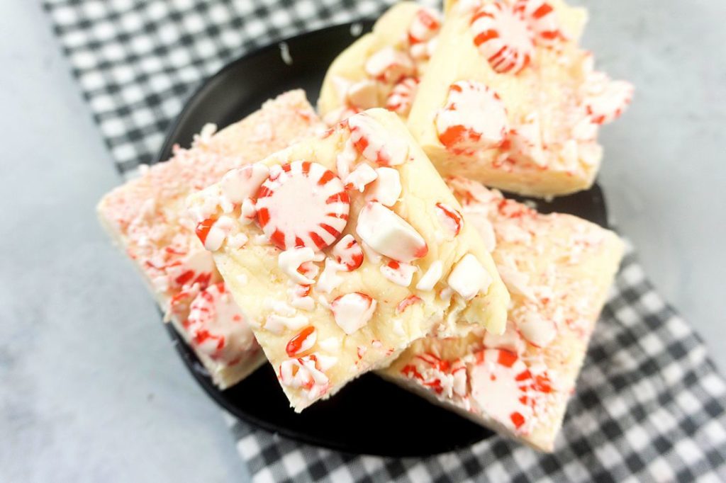 Peppermint Candy Fudge on a black plate with gray plaid napkin on a concrete backdrop