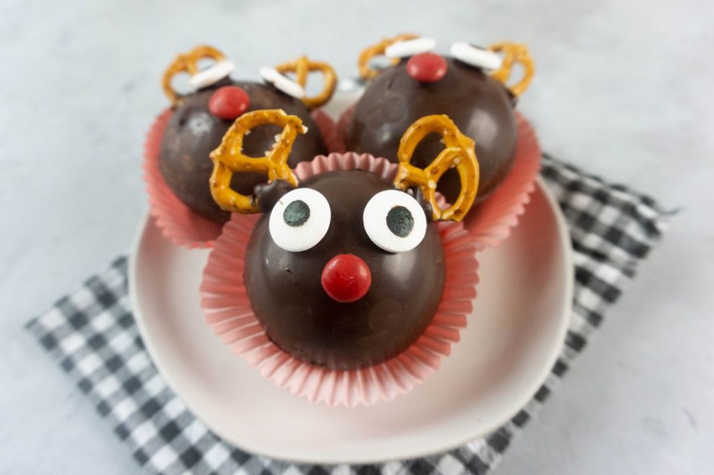 Rudolph Hot Chocolate Bombs on a white plate with gray plaid napkin and concrete backdrop