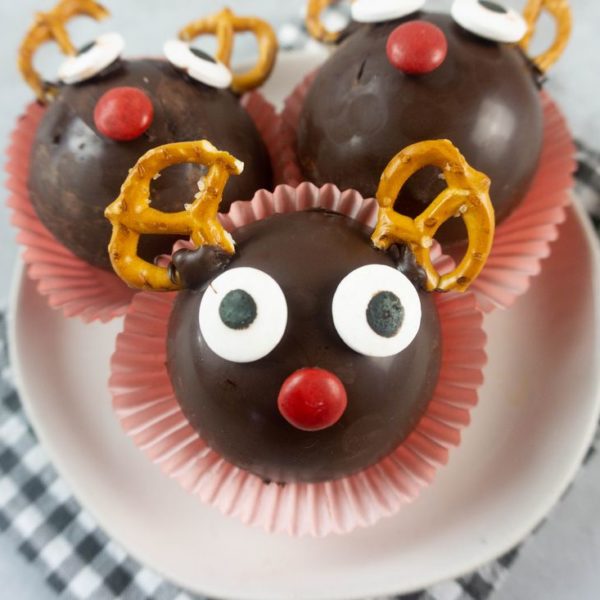 Rudolph Hot Chocolate Bombs on a white plate with gray plaid napkin and concrete backdrop