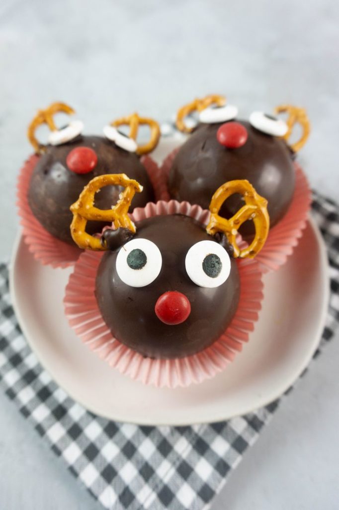 Rudolph Hot Chocolate Bombs on a white plate with gray plaid napkin and concrete backdrop