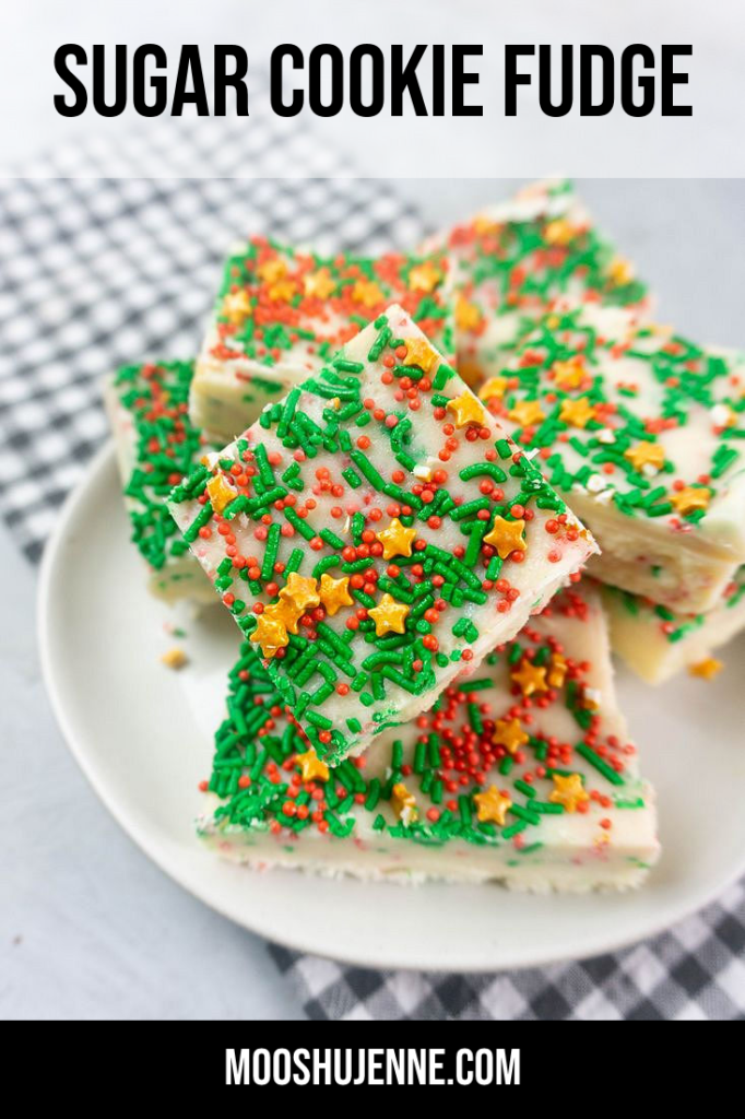 Sugar cookie fudge covered in Christmas sprinkles on a white plate with grey plaid napkin on a concrete back drop