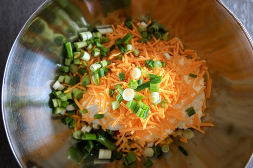 metal bowl with southwestern corn, cheese, green onions, sour cream and mayo