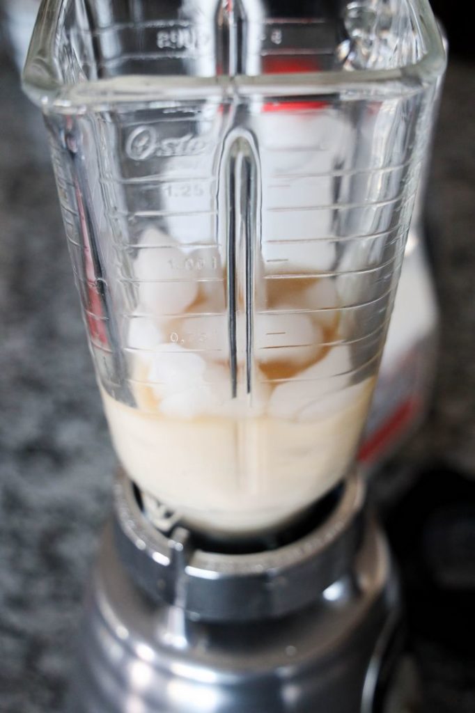 Milk, Espresso, and Ice in a blender with a milk jug in the back.