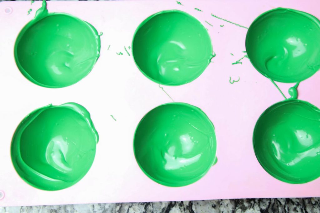 Dark green candy melts coating a pink dome mold