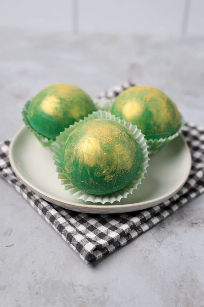 Irish Whiskey Hot Chocolate Bombs on a white plate with gray plaid napkin and concrete backdrop