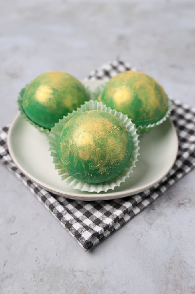 Irish Whiskey Hot Chocolate Bombs on a white plate with gray plaid napkin and concrete backdrop