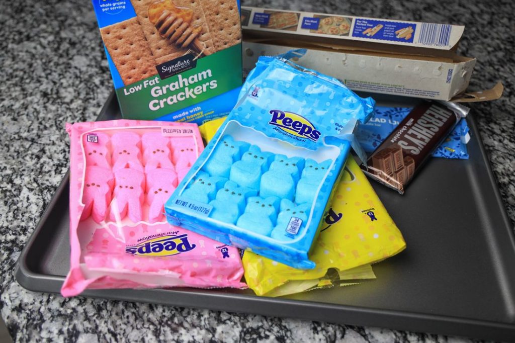 Items needed to make the peeps smores. Graham crackers, chocolate, peeps, and parchment paper.