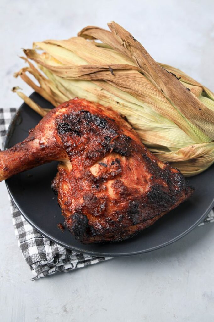 BBQ Picnic Chicken on a gray plate with gray plaid napkin on a concrete backdrop