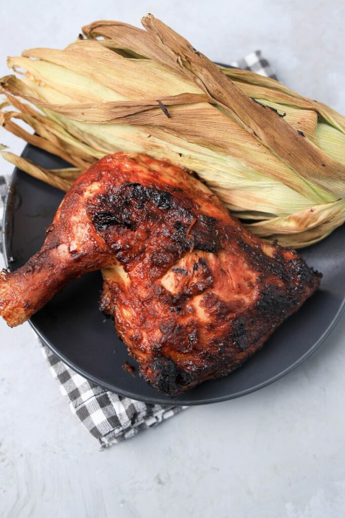 BBQ Picnic Chicken on a gray plate with gray plaid napkin on a concrete backdrop