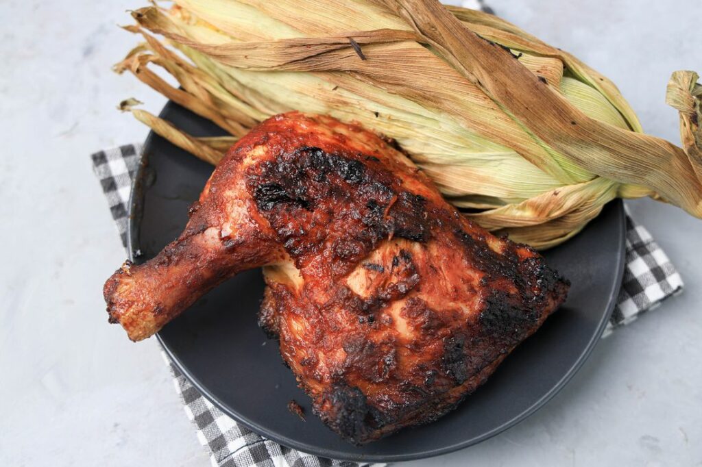 BBQ Picnic Chicken on a gray plate with gray plaid napkin on a concrete backdrop