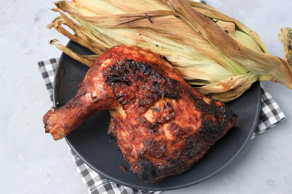 BBQ Picnic Chicken on a gray plate with gray plaid napkin on a concrete backdrop